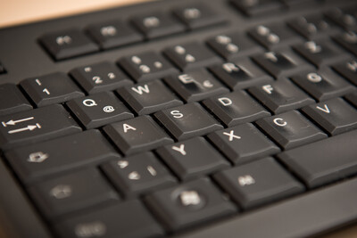 Schwarze Computertastatur in Nahaufnahme, Fokus auf Buchstabentasten in diagonaler Perspektive.