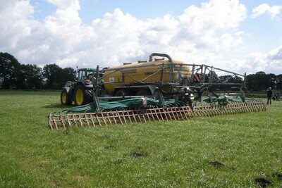 Ausbringung mit Schleppschlauch auf Grünland - © Jelko Djuren Traktor mit großem gelbem Tankanhänger und Verteiler auf einem grünen Feld unter bewölktem Himmel.